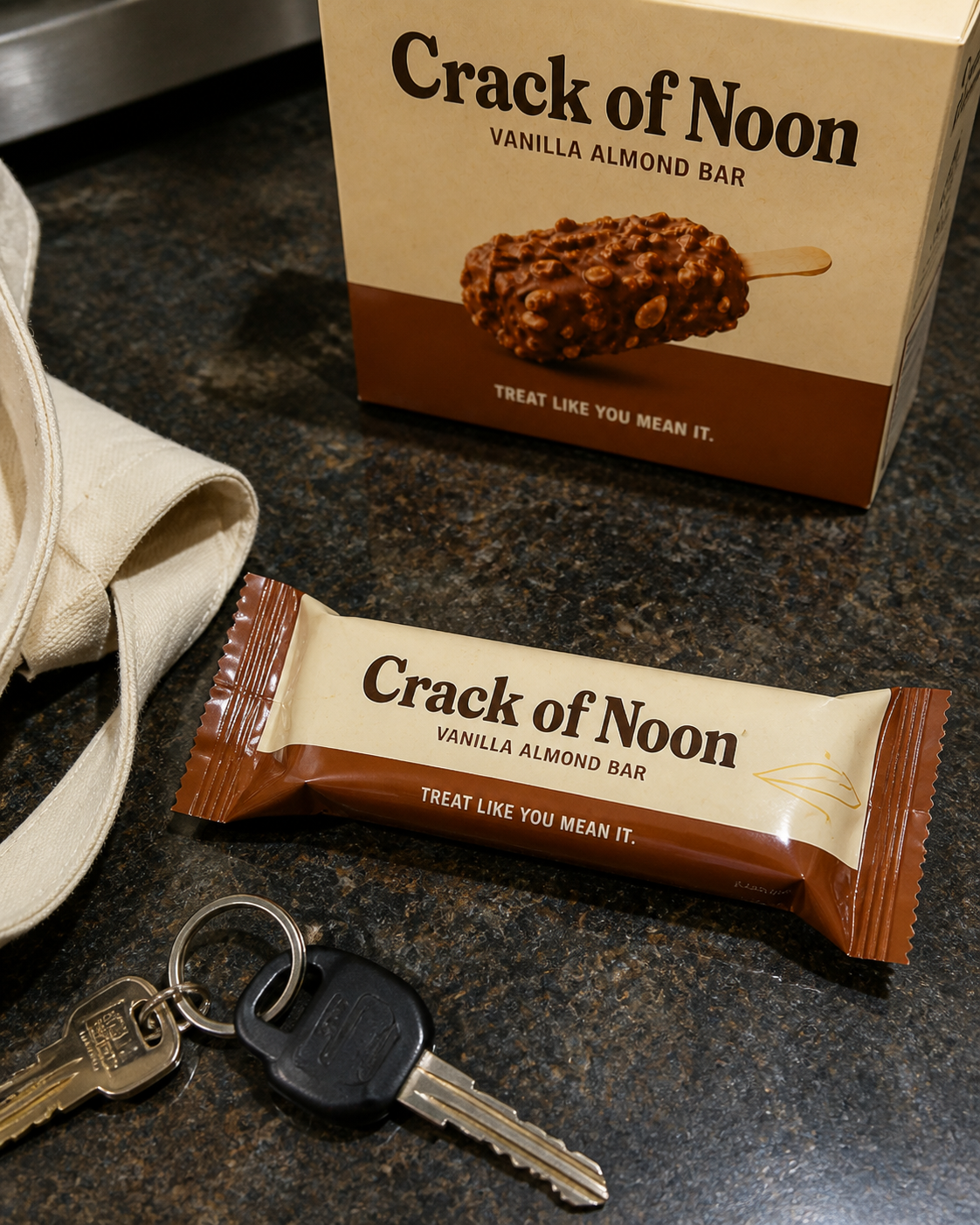 Wrapped Crack of Noon concept bar beside its carton and a set of keys on a dark counter.